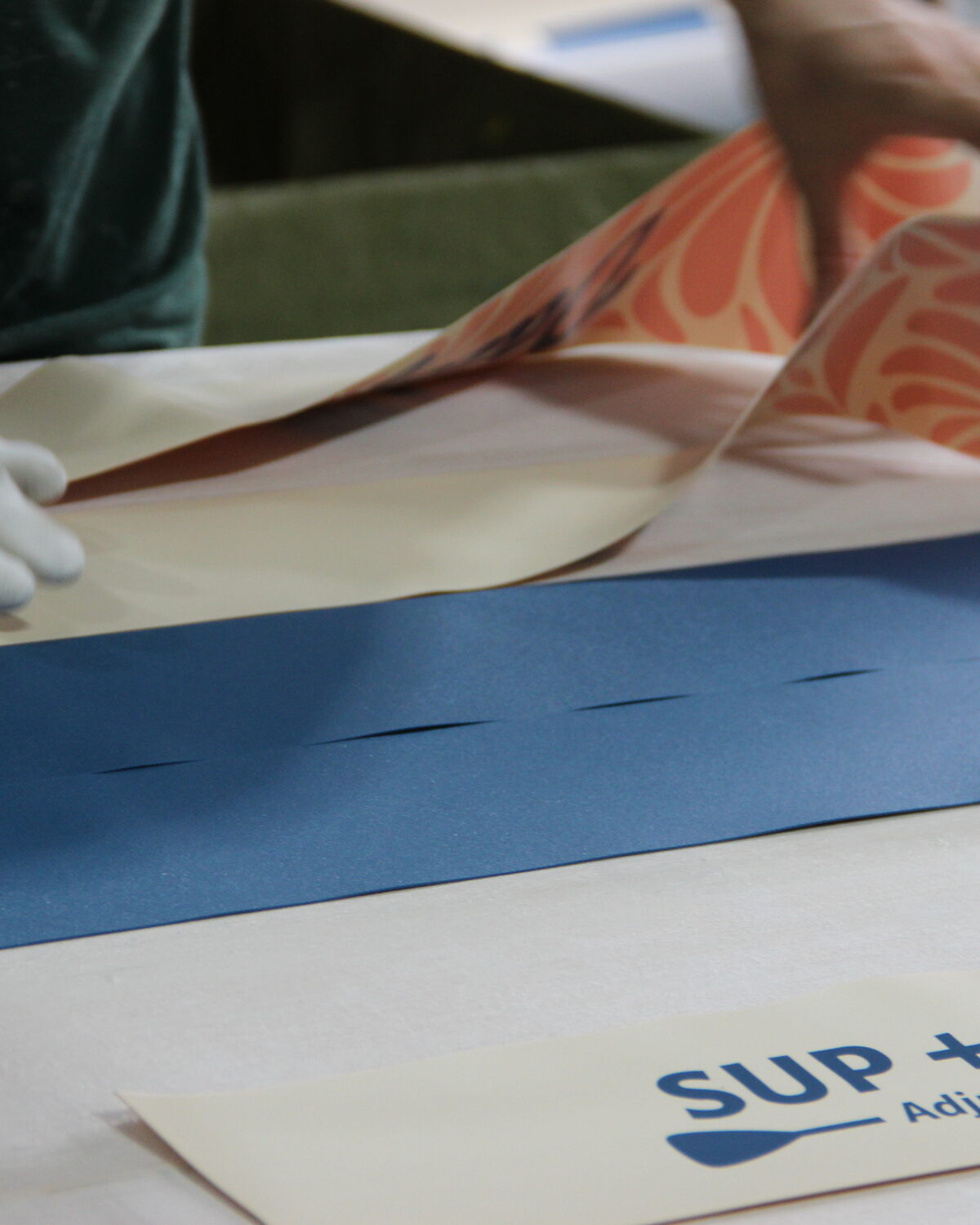 Printed deck graphic material being positioned on a white board deck.