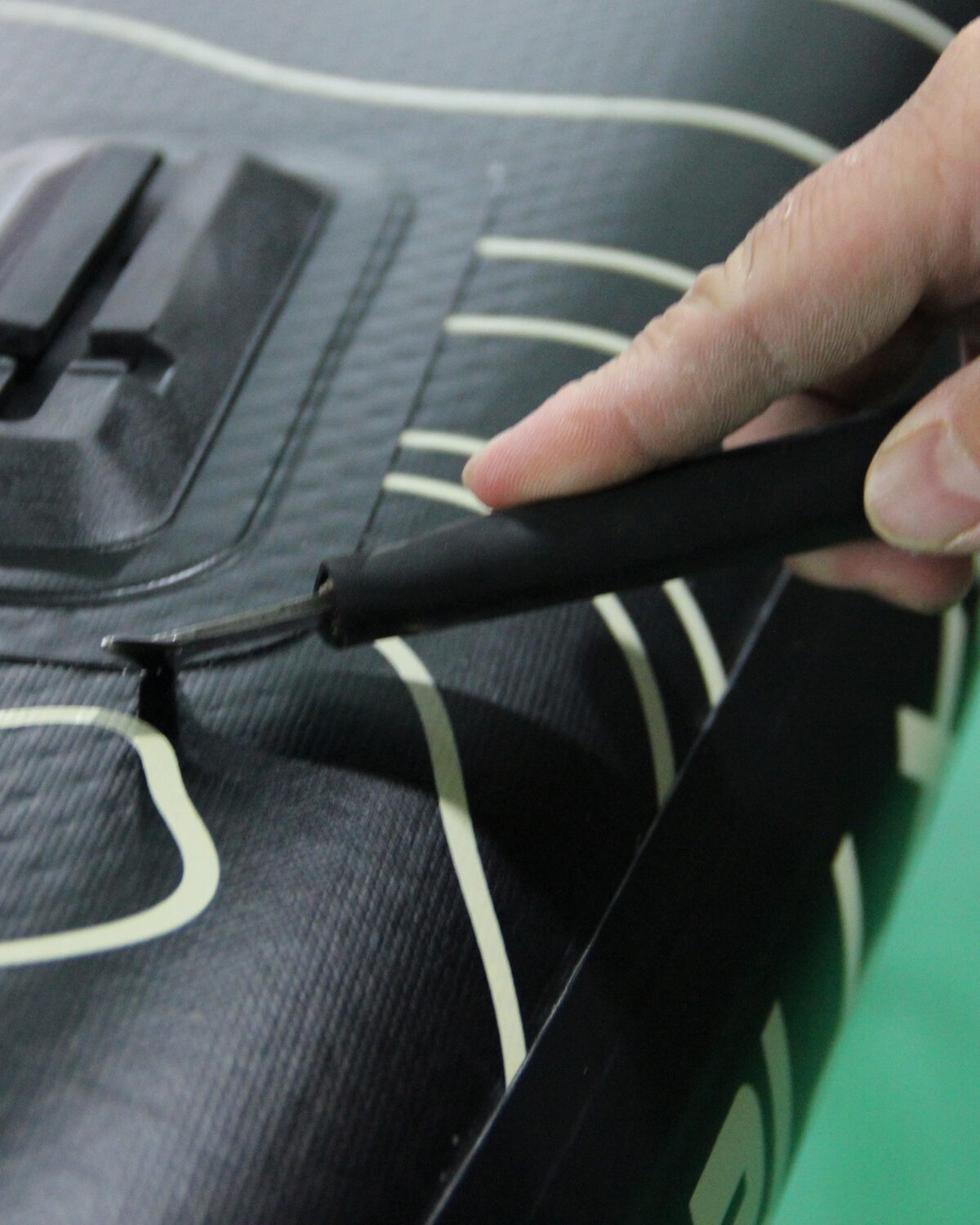 A hand smoothing a mount area on a black board deck.
