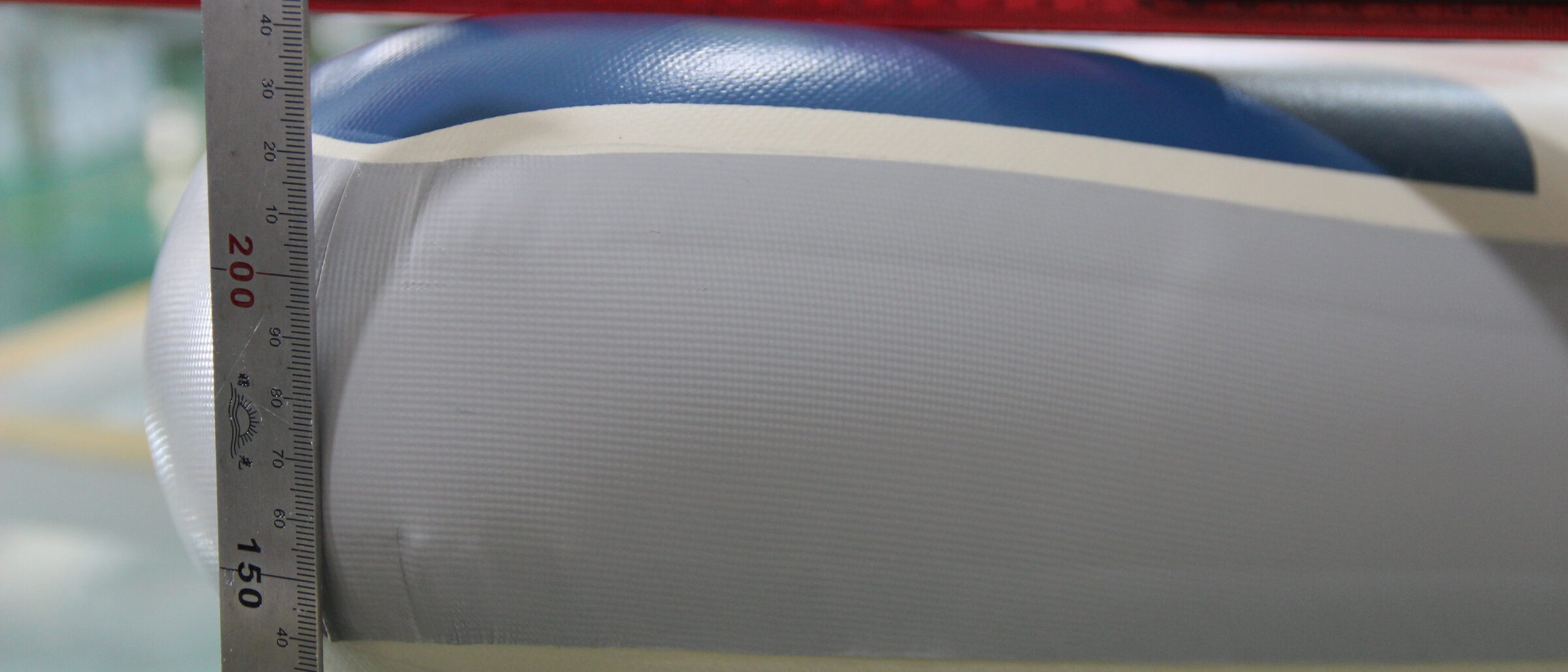 A measuring tool held against the rail of a paddle board during a dimensional check.