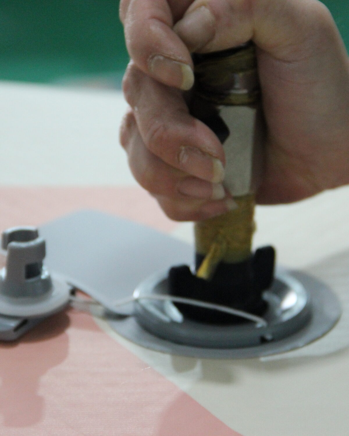 A hand working adhesive around the valve area of an orange board.